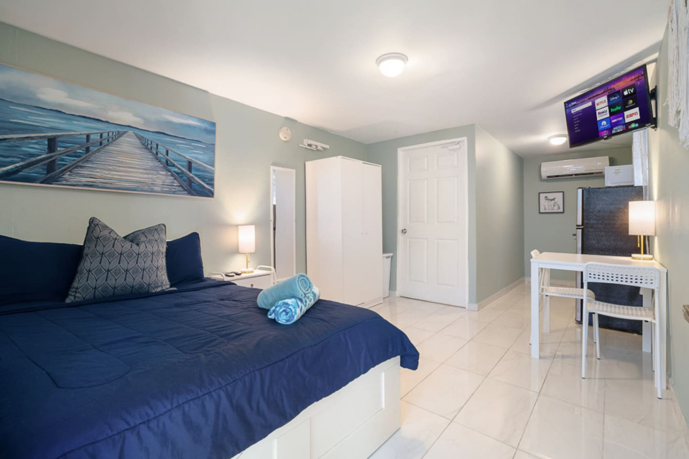 Bedroom with a blue bedspread and a painting on the wall — Casa Juno I: Private Courtyard Studio, Santurce
