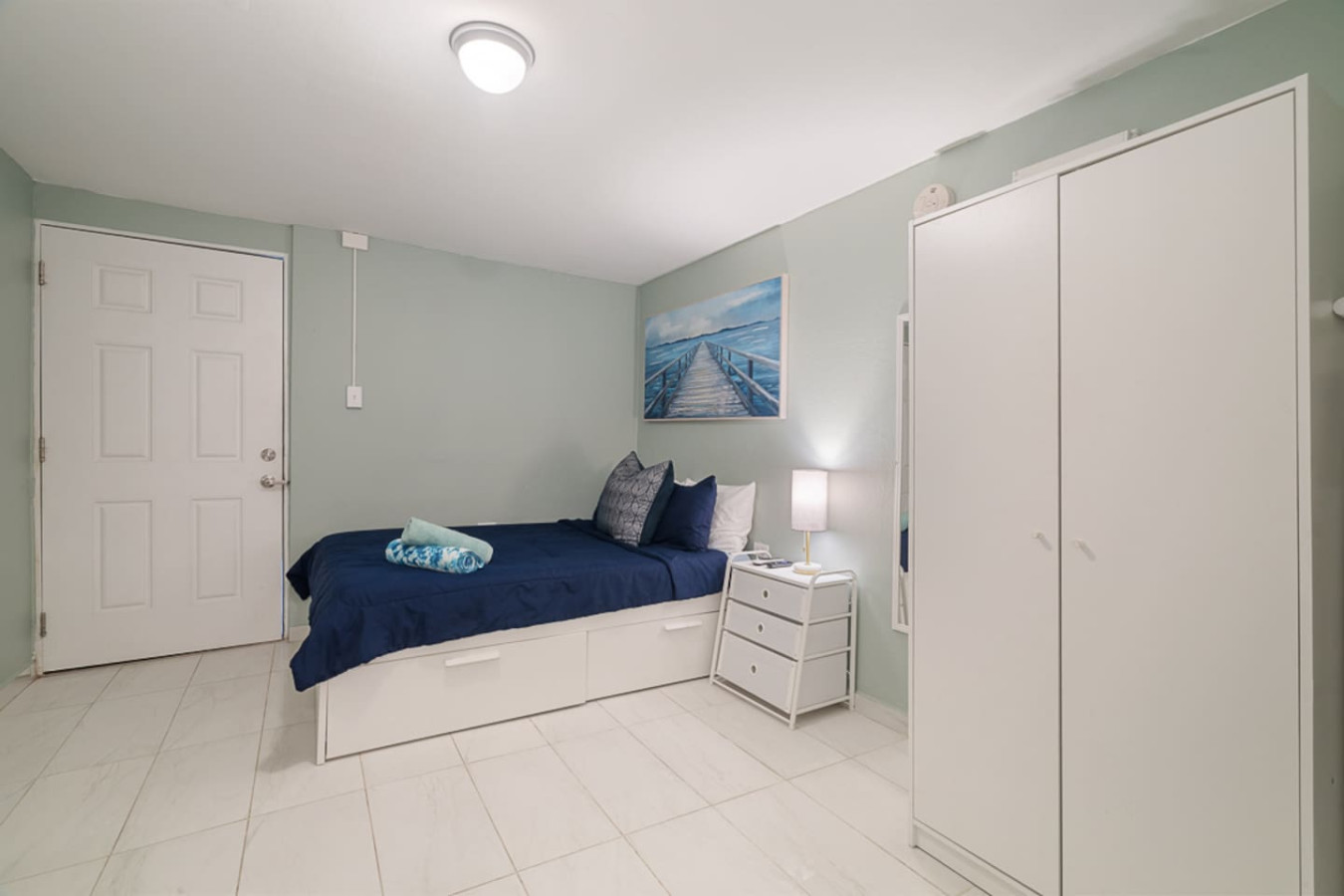 Bedroom with a blue bedspread and a painting on the wall (bedroom 3) — Casa Juno I: Private Courtyard Studio, Santurce