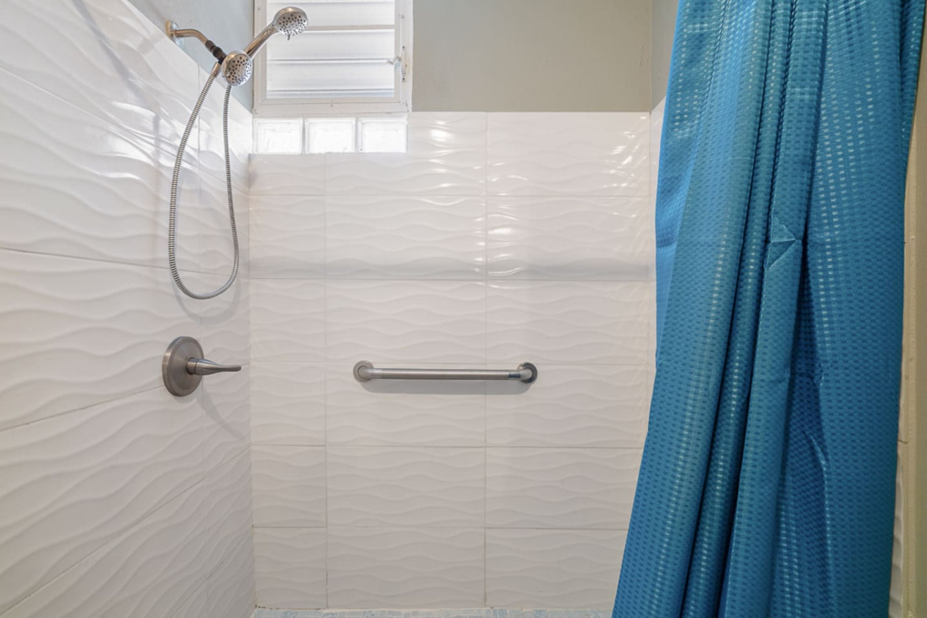 Bathroom with a shower and a blue shower curtain — Casa Juno I: Private Courtyard Studio, Santurce