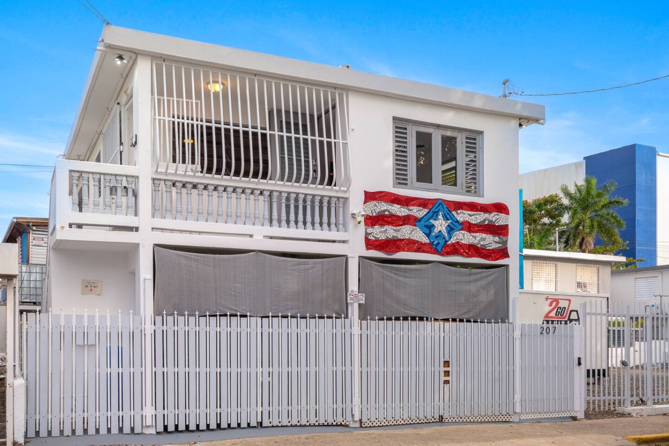 White house with a flag on the front balcony — Romero Studio San juan near beach, Santurce