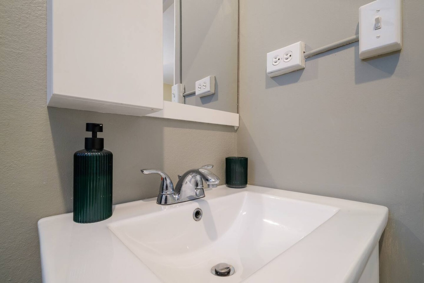 White bathroom sink with a silver faucet and a green bottle on the counter — Romero Studio San juan near beach, Santurce