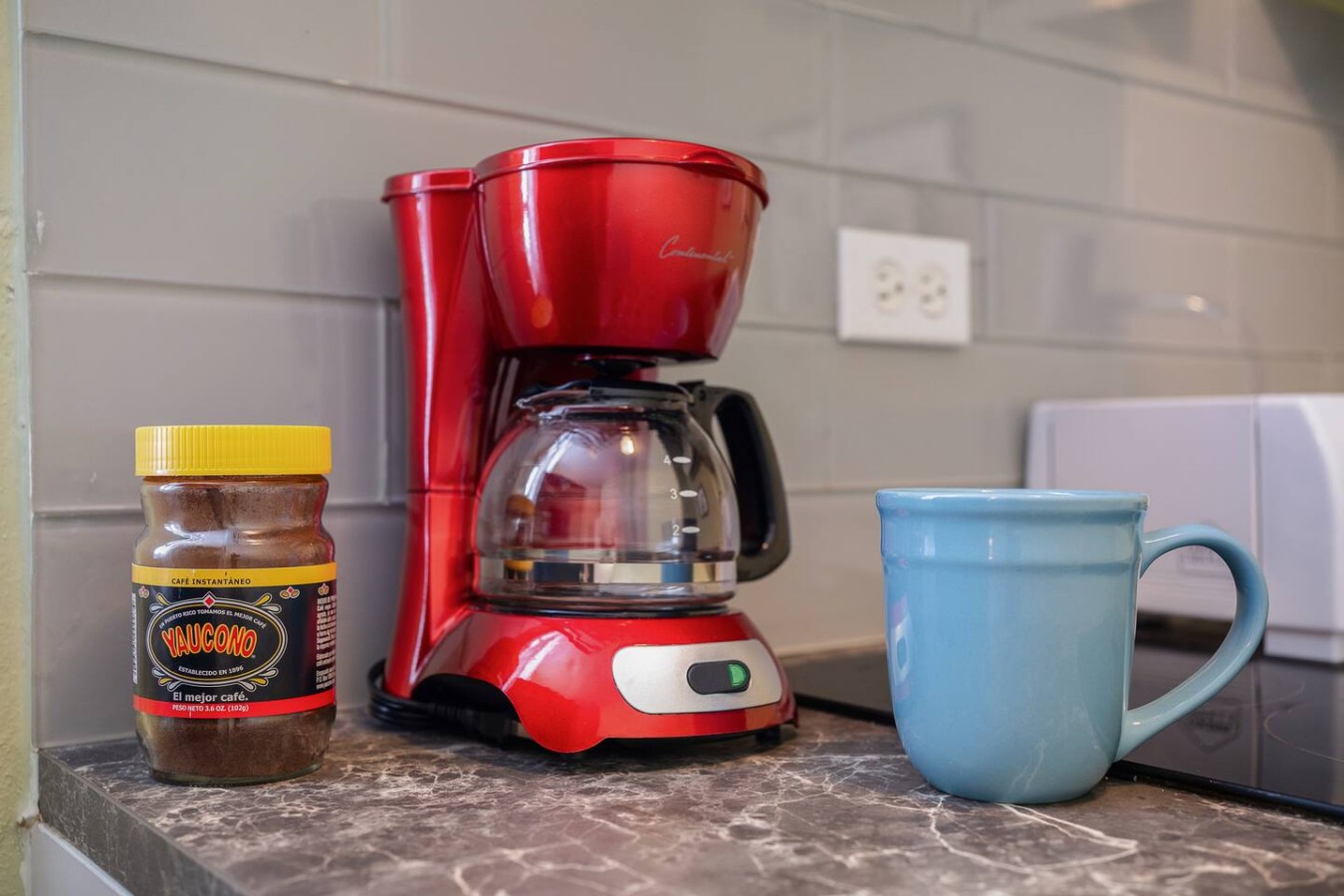 Red coffee maker on a counter next to a blue cup — Romero Studio San juan near beach, Santurce