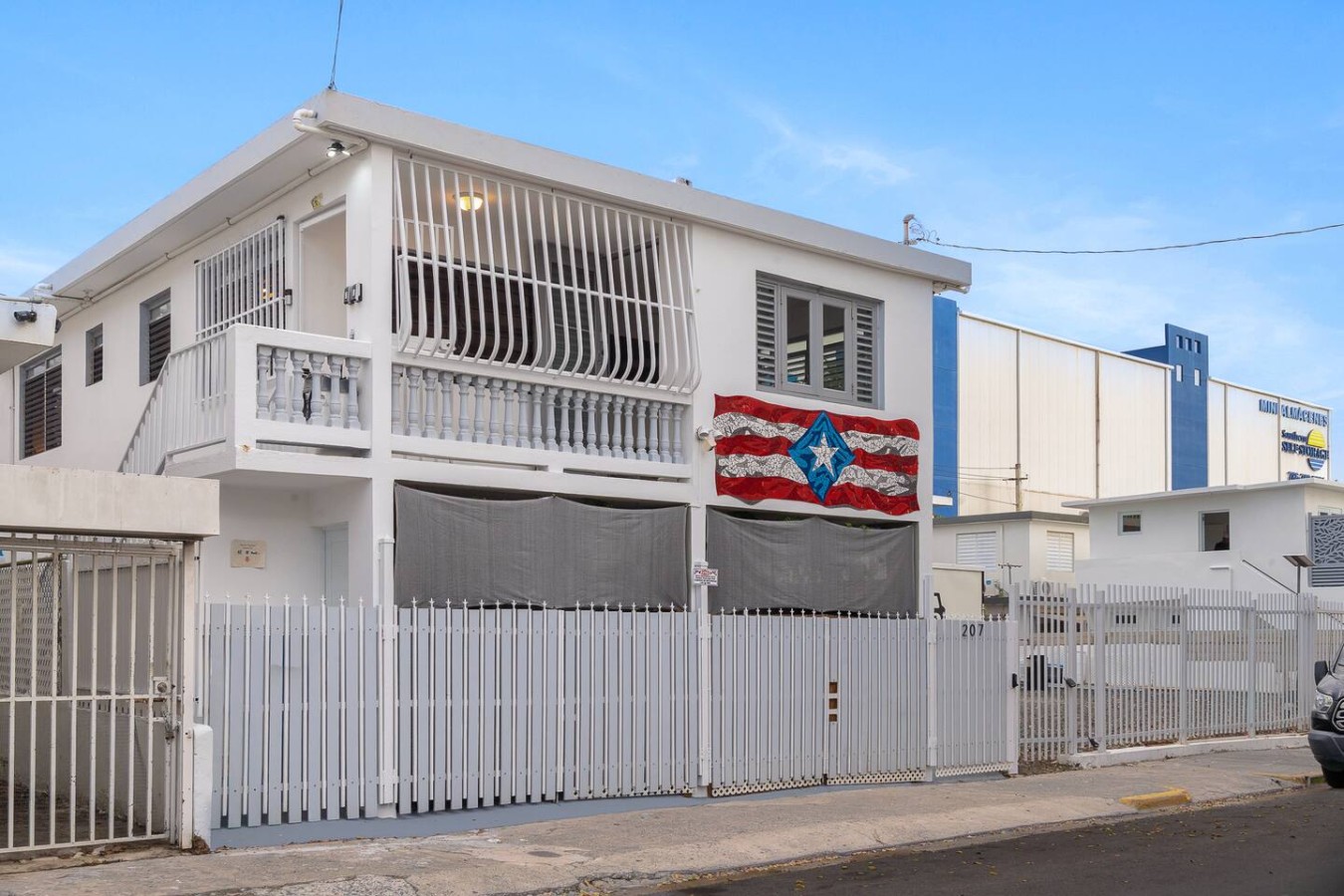 White house with a balcony and a flag on the front — Romero Studio San juan near beach, Santurce