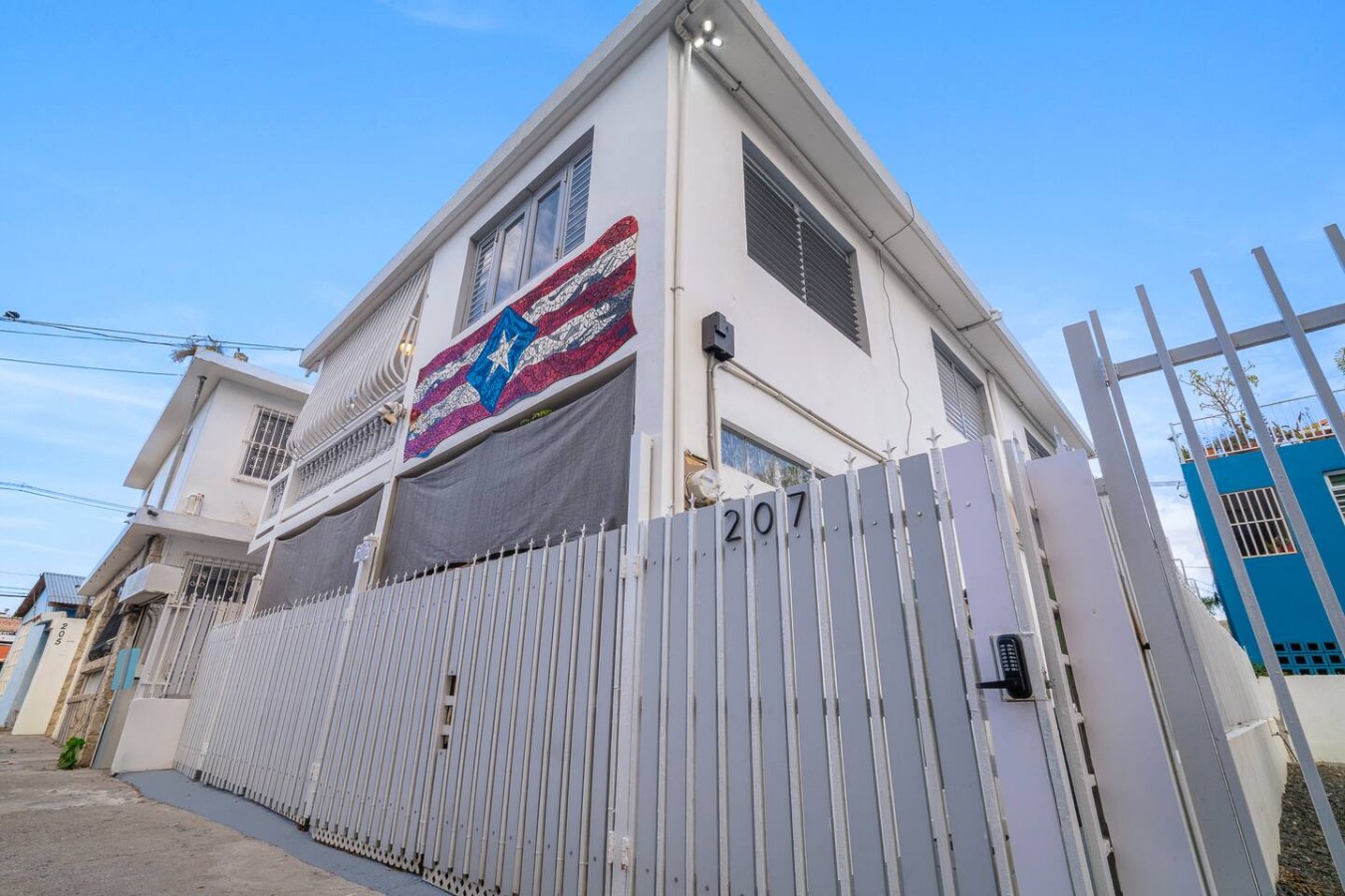 White house with a Puerto Rican flag on the front door — Romero Studio San juan near beach, Santurce