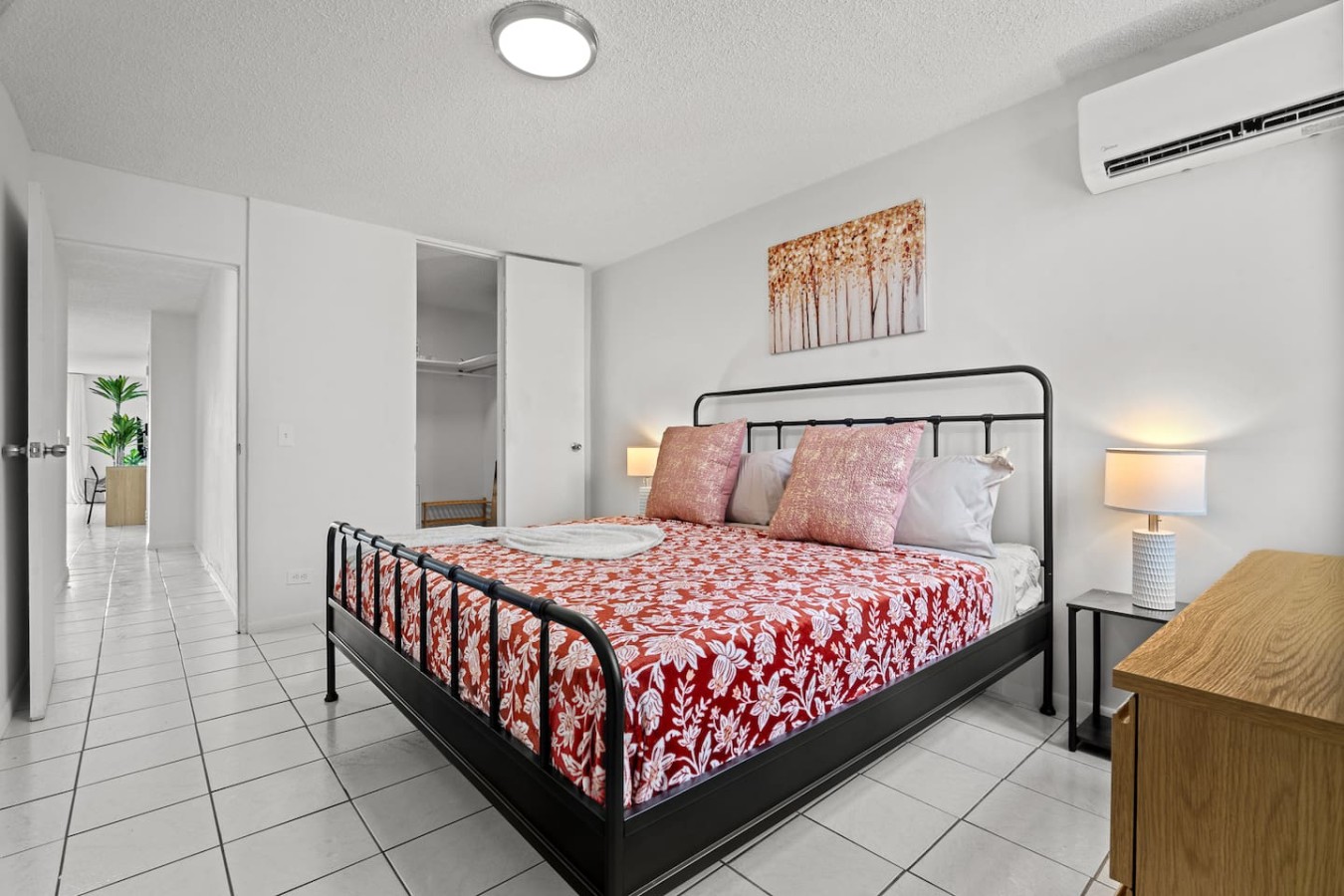 Bedroom with a black metal bed and red floral bedspread — High-Rise Condado Suite | Ocean Views & PR Skyline, Condado