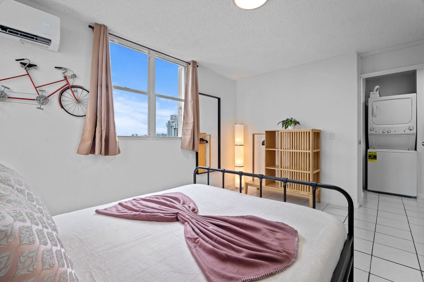 Bedroom with a pink blanket on the bed and a window view of — High-Rise Condado Suite | Ocean Views & PR Skyline, Condado