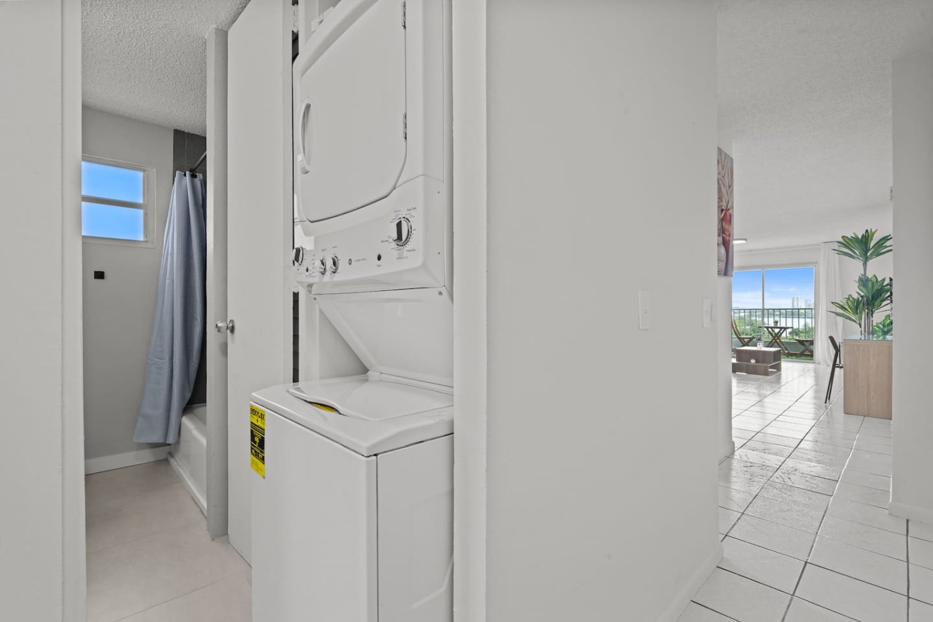 Laundry closet with a stacked washer and dryer — High-Rise Condado Suite | Ocean Views & PR Skyline