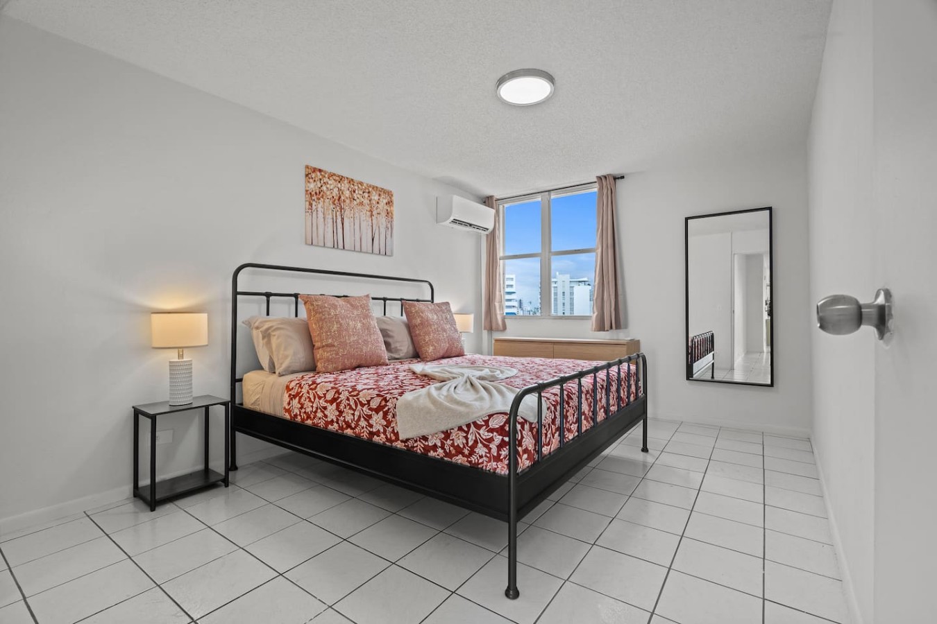 Bedroom with a black metal bed and a red floral bedspread — High-Rise Condado Suite | Ocean Views & PR Skyline, Condado