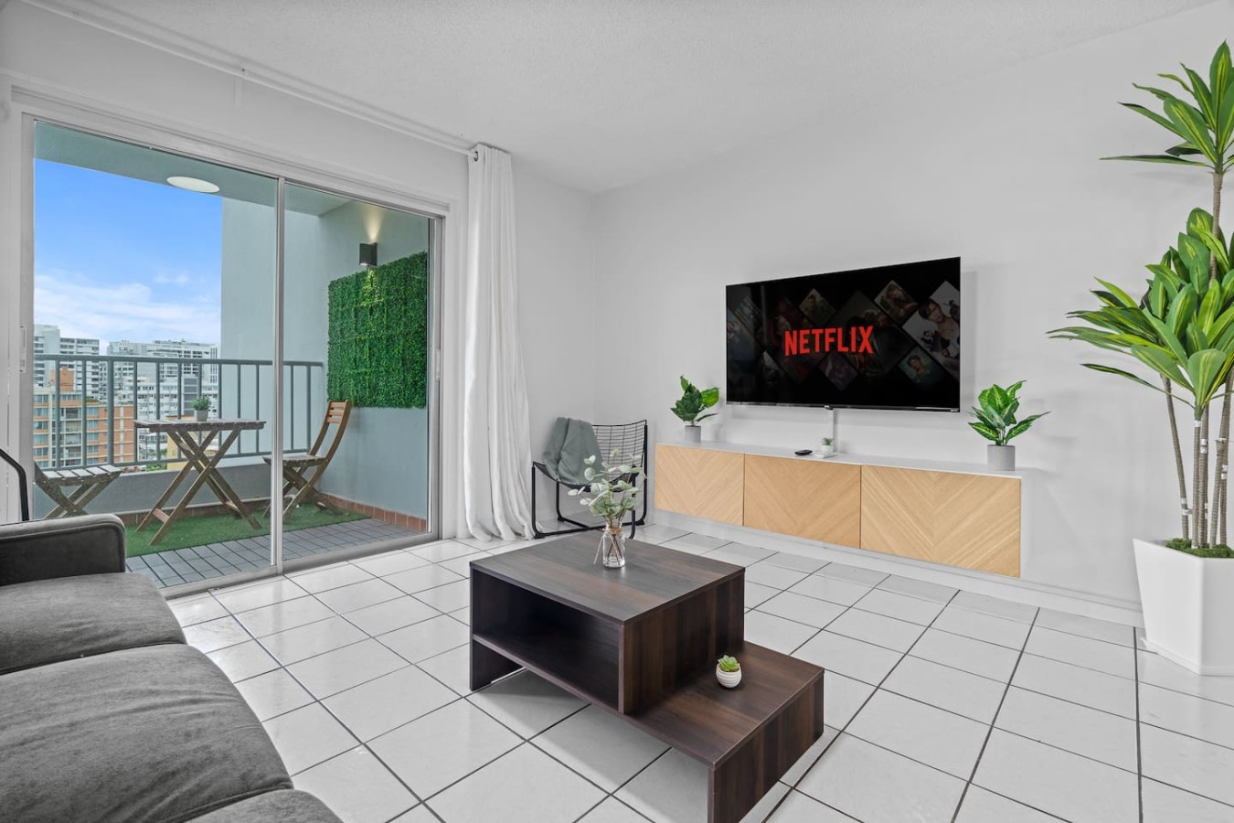 Living room with a TV and a sliding door to the balcony — High-Rise Condado Suite | Ocean Views & PR Skyline
