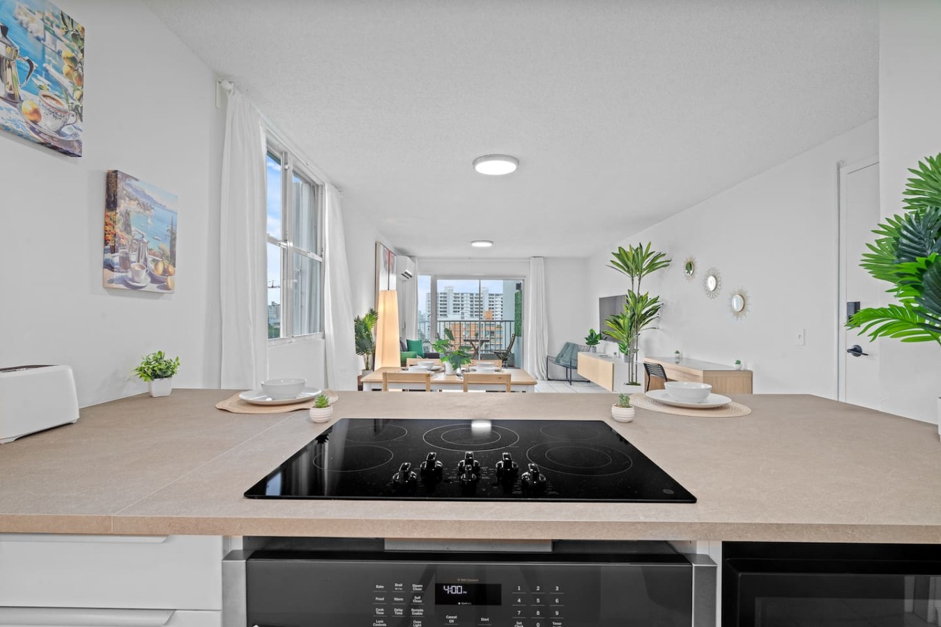 Kitchen peninsula with a cooktop, open to the living room — High-Rise Condado Suite | Ocean Views & PR Skyline