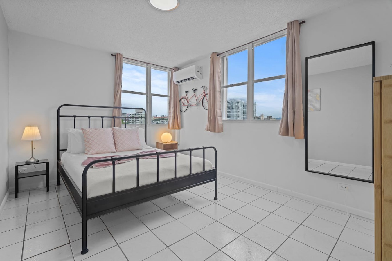 Bedroom with a black bed and a window with a view of the city — High-Rise Condado Suite | Ocean Views & PR Skyline, Condado