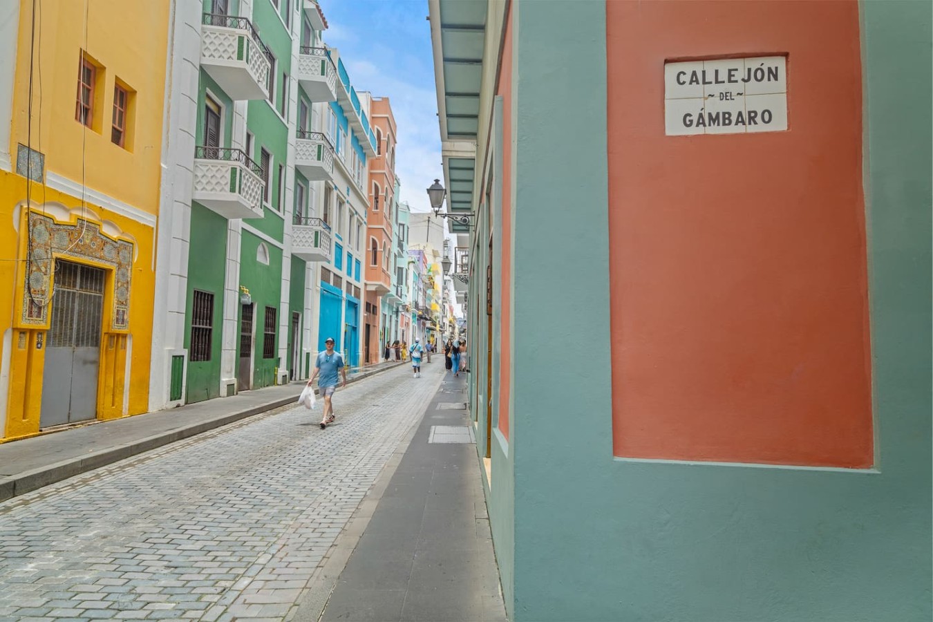 Man walking on a street with a blue building in the background — Bellavista Galleria | Old San Juan