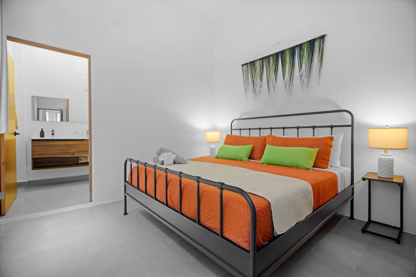 Bedroom with a black metal bed frame and orange pillows — Bellavista Galleria | Old San Juan, Old San Juan