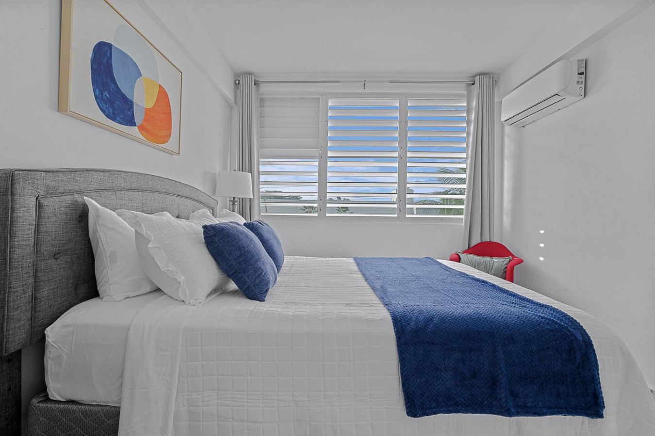 Bedroom with a blue blanket on the bed and a painting on the wall — Ocean Park 2BR · Steps to Beach & Dining, Santurce