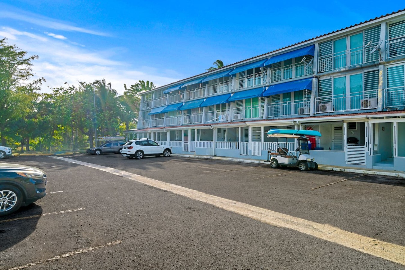 Three-storey building with blue awnings and parking — Beachside Villa Dorado Pool Beach Access