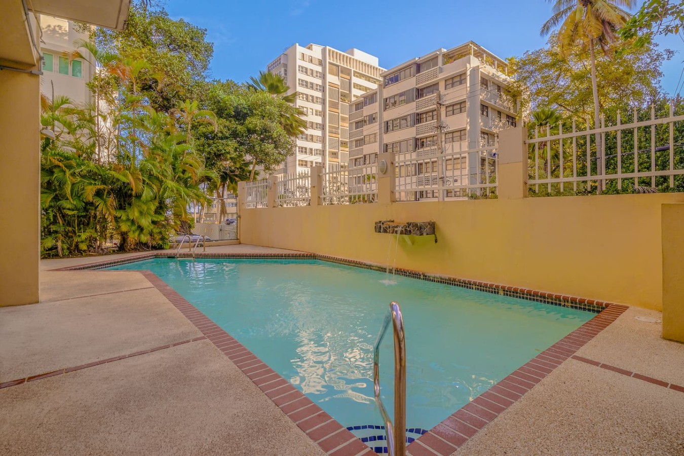 Pool area with a fence and a view of the city — Casa Celeste | Sunlit Tropical Stay in Condado, Santurce