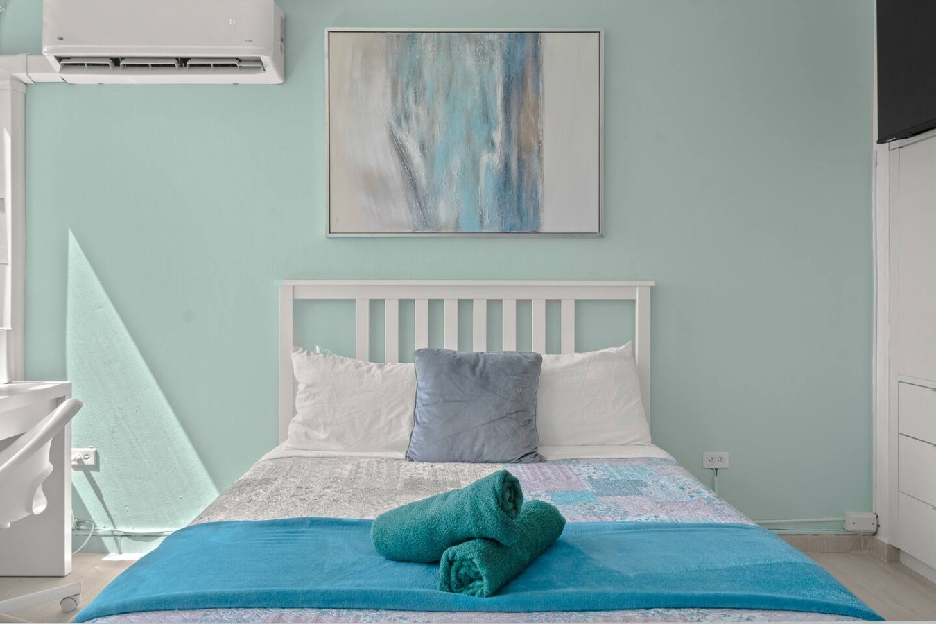 Bedroom with a white bed, blue sheets, and a painting on the wall — Casa Celeste | Sunlit Tropical Stay in Condado, Santurce