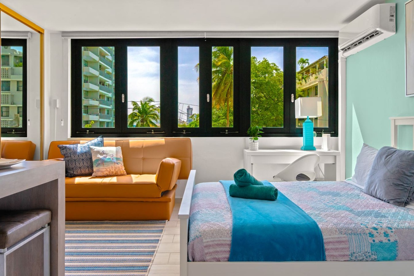 Bedroom with a blue bedspread and a view of the city — Casa Celeste | Sunlit Tropical Stay in Condado, Santurce