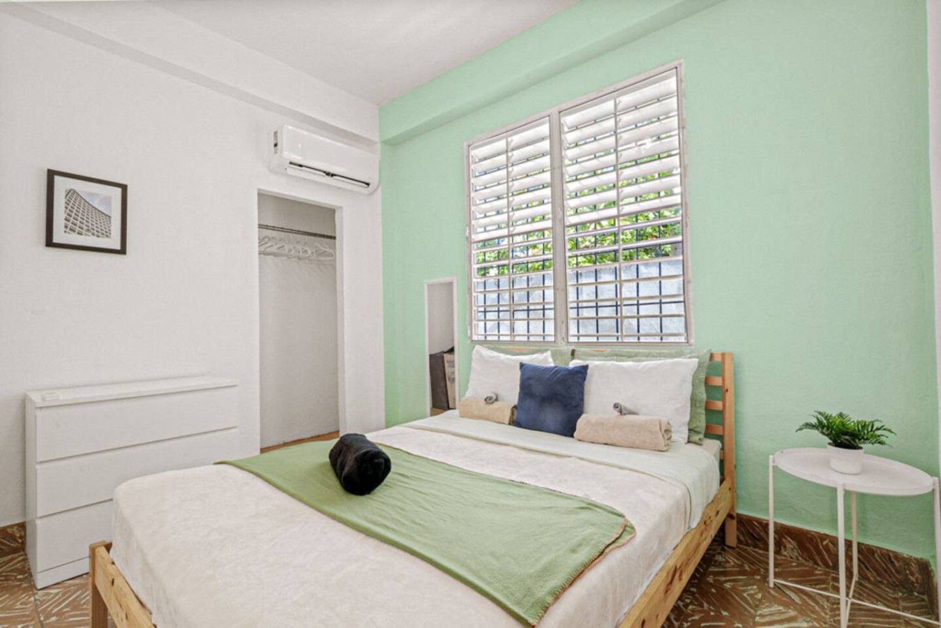 Bedroom with a green bedspread and a black cat on it — Virelia | Colorful San Juan Escape for Four, Santurce