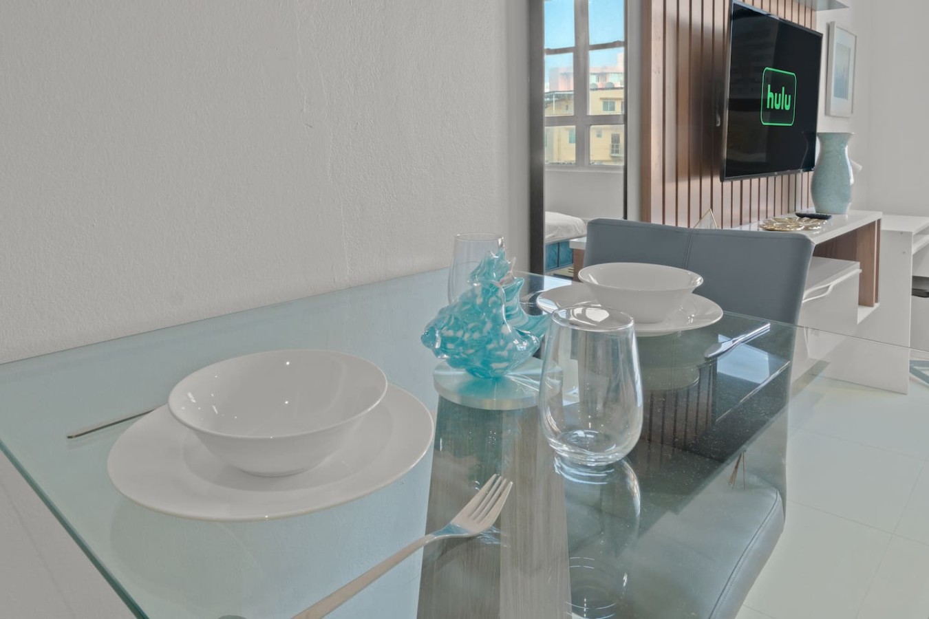 Dining area with a glass table set for two — T-Mobile District San Juan Next to Beach