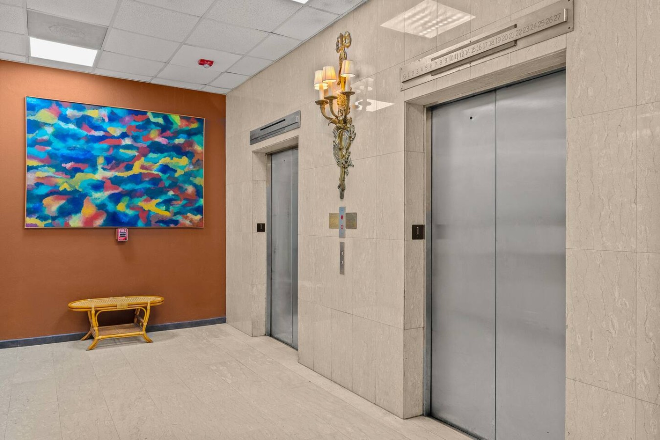 Building's elevator lobby with a painting and a bench — Caribbean Sea View | T-Mobile District Free Parking, San Juan