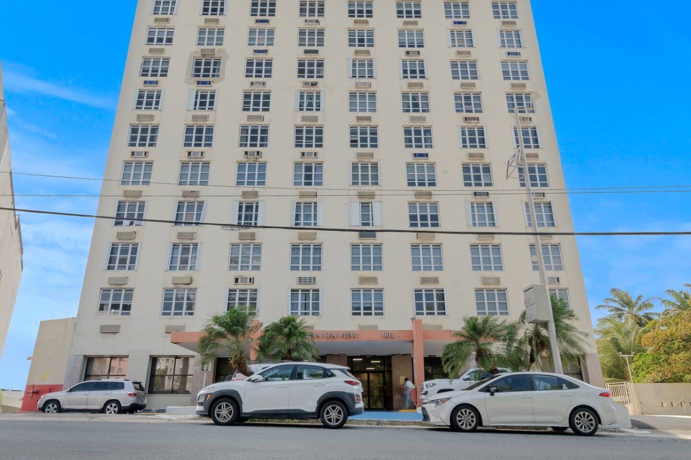 White SUV parked in front of a tall white building — Caribbean Sea View | T-Mobile District Free Parking, San Juan