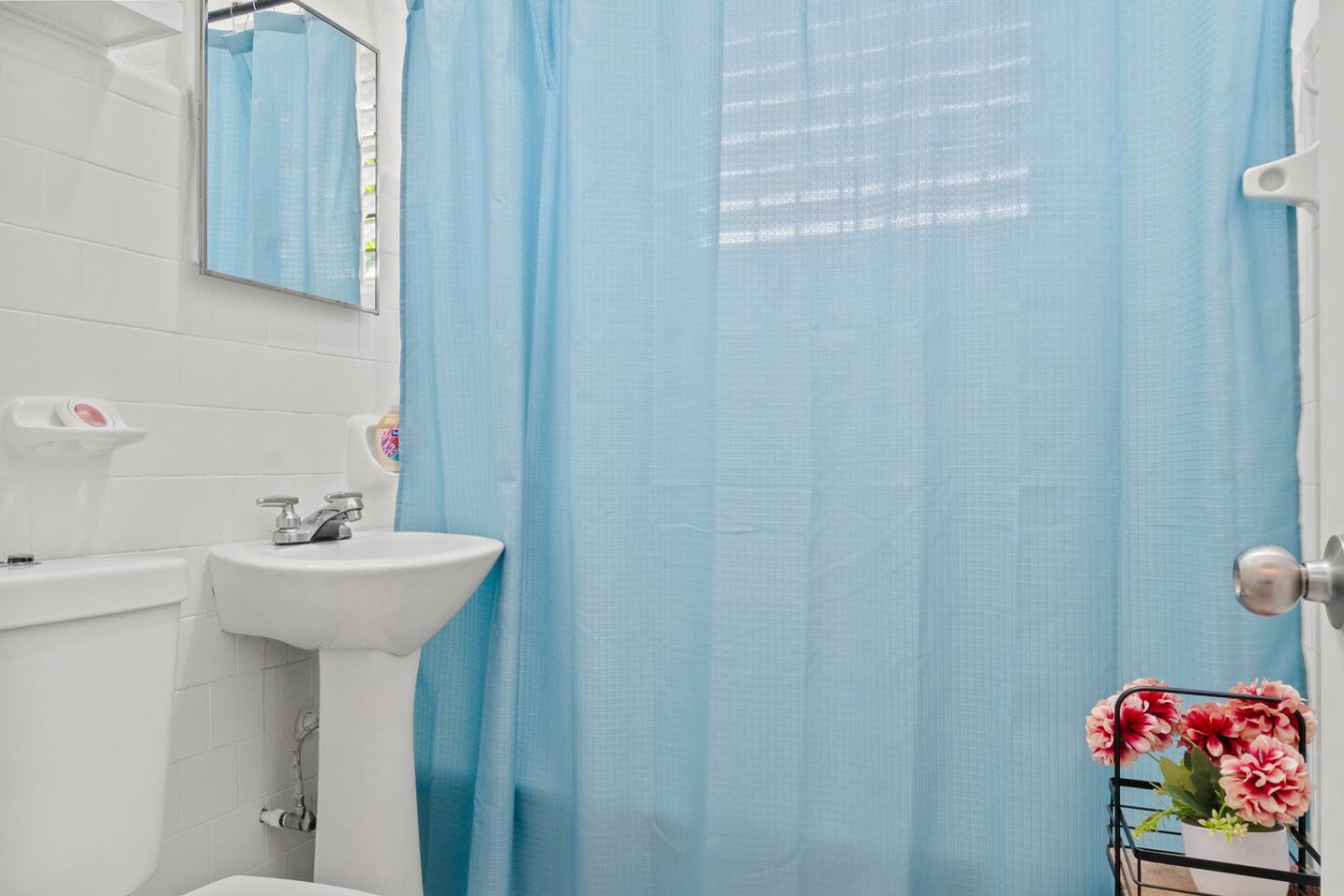 Bathroom with a pedestal sink and a blue shower curtain — Aurelia | Three Bedrooms in the Heart of San Juan, Santurce
