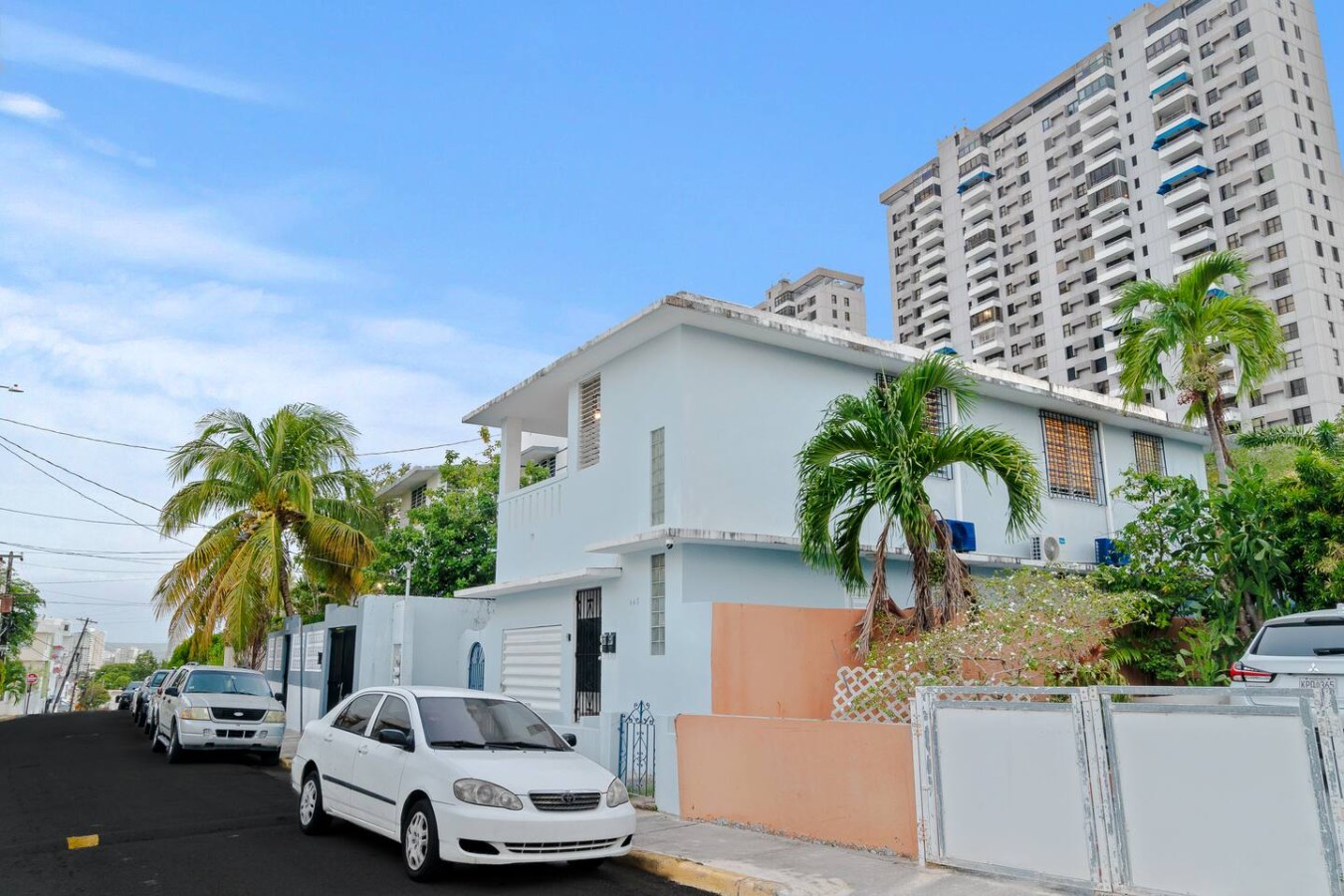 White two-story house with palm trees, seen from the street — Aurelia | Three Bedrooms in the Heart of San Juan, Santurce