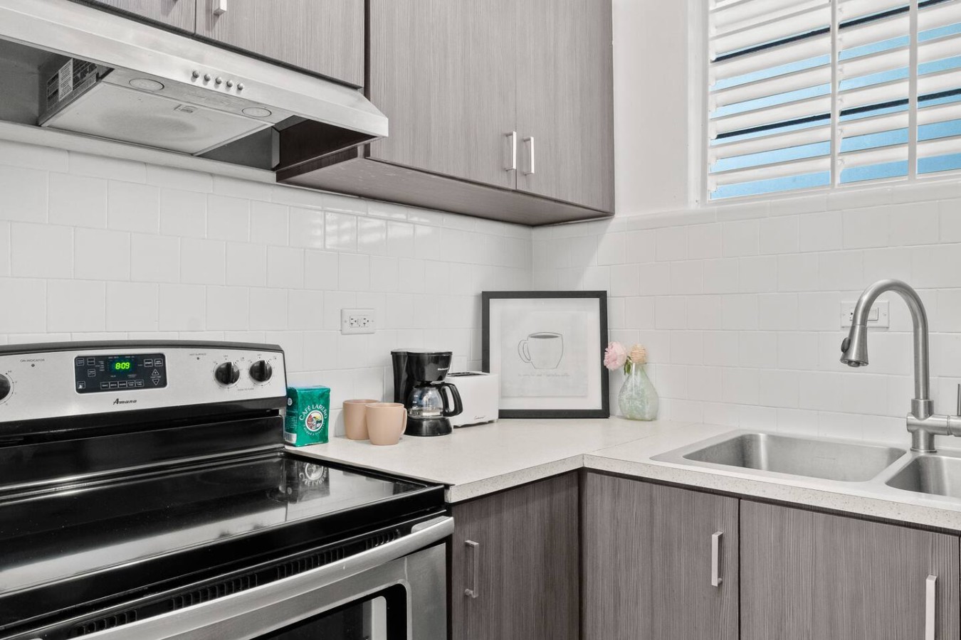Kitchen with an electric stove, a double sink and gray cabinets — Aurelia | Three Bedrooms in the Heart of San Juan, Santurce