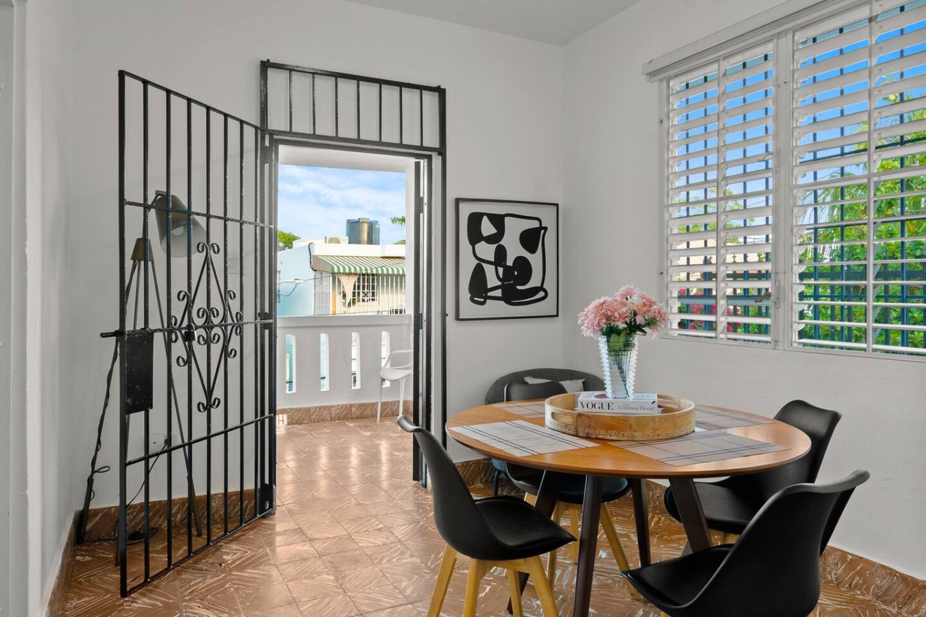 Round dining table beside an open iron gate to the porch — Aurelia | Three Bedrooms in the Heart of San Juan, Santurce