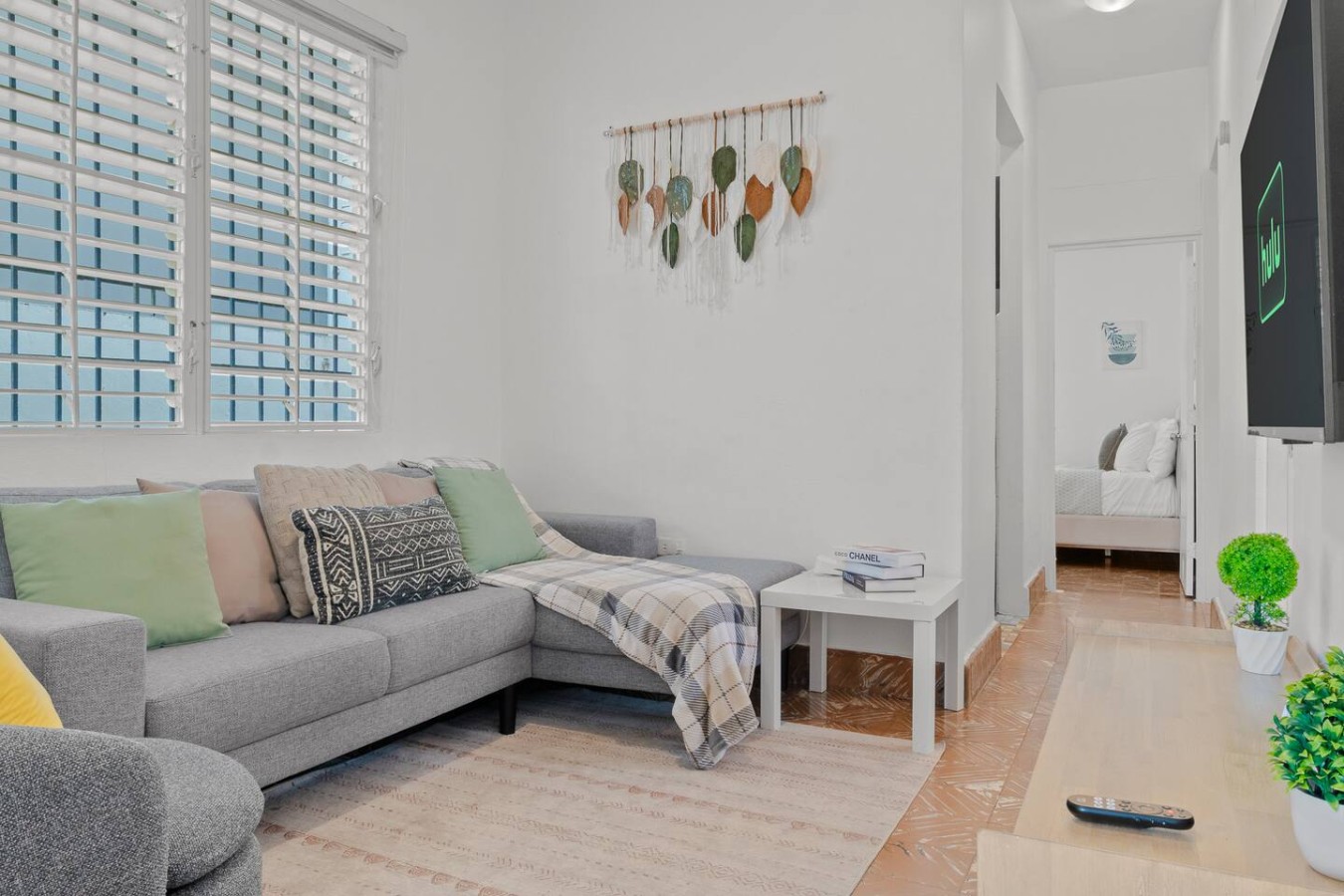 Living room with a gray sectional sofa and a leaf wall hanging — Aurelia | Three Bedrooms in the Heart of San Juan, Santurce