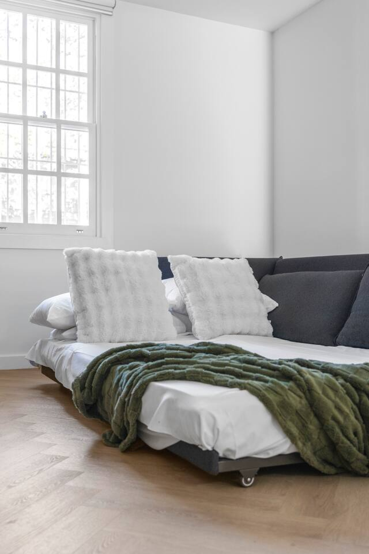 A stylish and cozy sofa bed setup, perfect for relaxation and functionality. The plush pillows and soft blanket add warmth to the modern space. By Superhostly