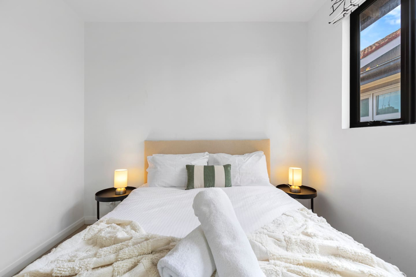 A cozy and modern queen bedroom with soft neutral tones, ambient lighting, and plush bedding, creating a serene and relaxing atmosphere. By Superhostly