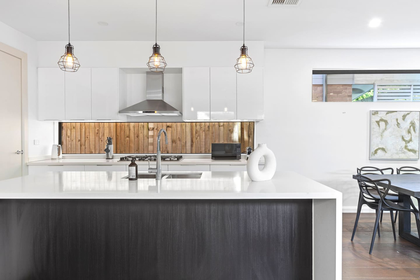 Modern elegance meets functionality in this stunning kitchen! Featuring sleek white cabinetry, stylish pendant lighting, and a spacious island bench—perfect for entertaining. By Superhostly