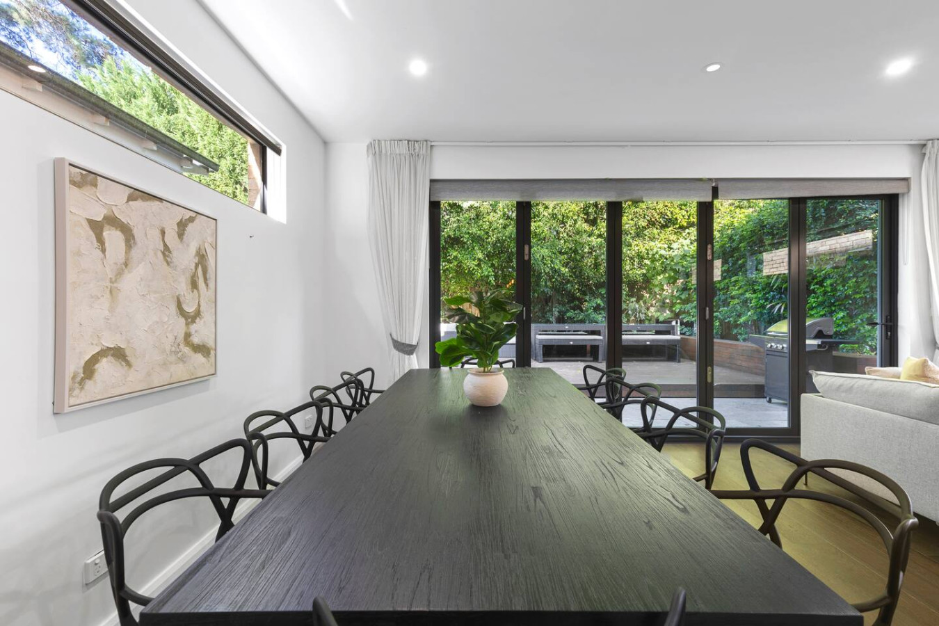 Gather in style! This spacious dining area features a sleek black table, modern seating, and seamless indoor-outdoor flow to a lush private patio with a BBQ. Perfect for shared meals and memorable moments. Book your stay today!