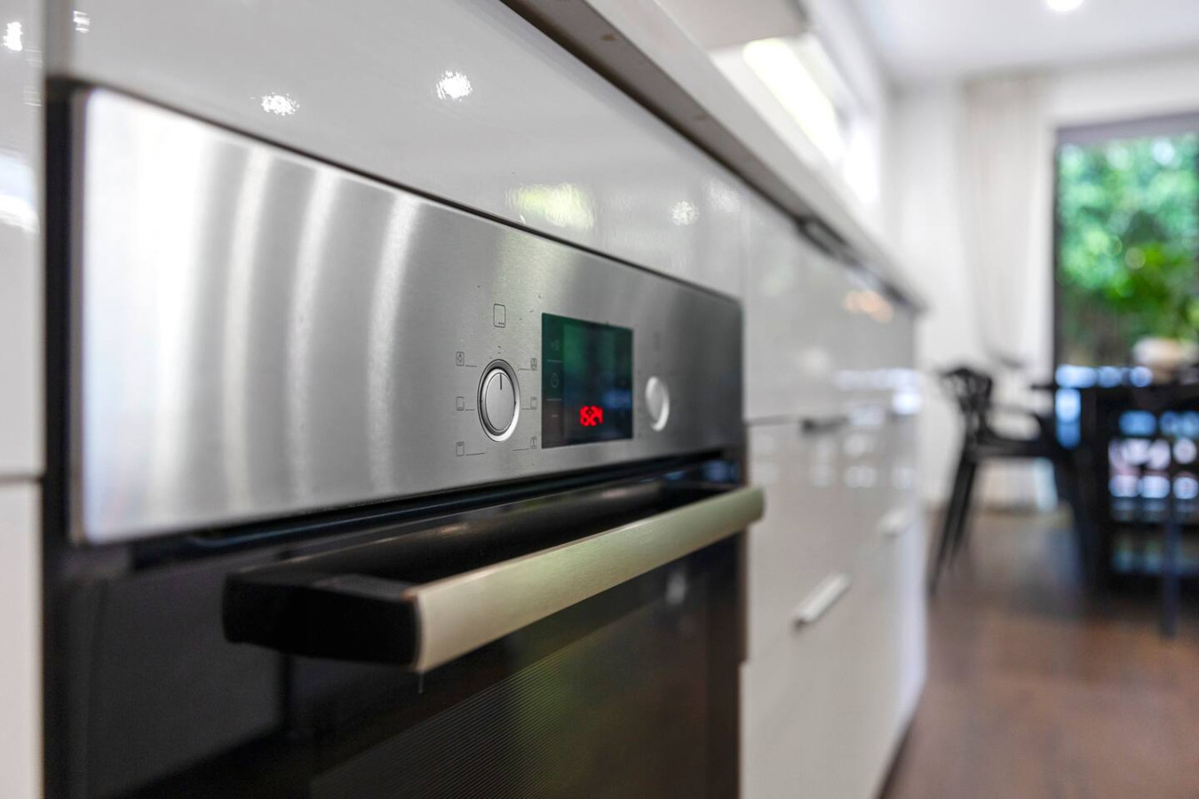Modern built-in stainless steel oven with a digital display, seamlessly integrated into a sleek kitchen.
