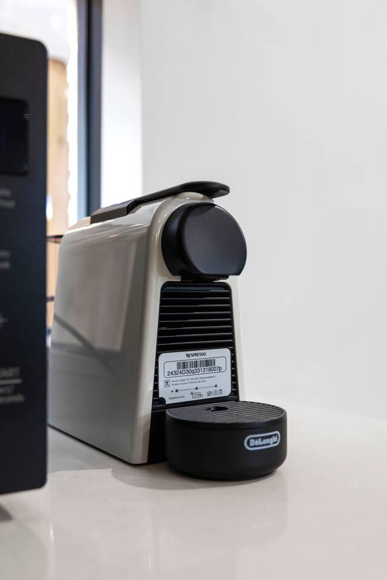 A sleek and modern Nespresso coffee machine sits on a pristine countertop, ready to brew a fresh cup of coffee. The compact design and neutral color make it a stylish and functional addition to the kitchen space. By Superhostly
