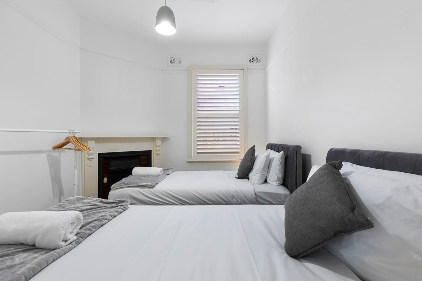 A cozy twin single bedroom featuring two plush single beds with soft gray accents, a charming fireplace, and a warm, inviting atmosphere. By Superhostly