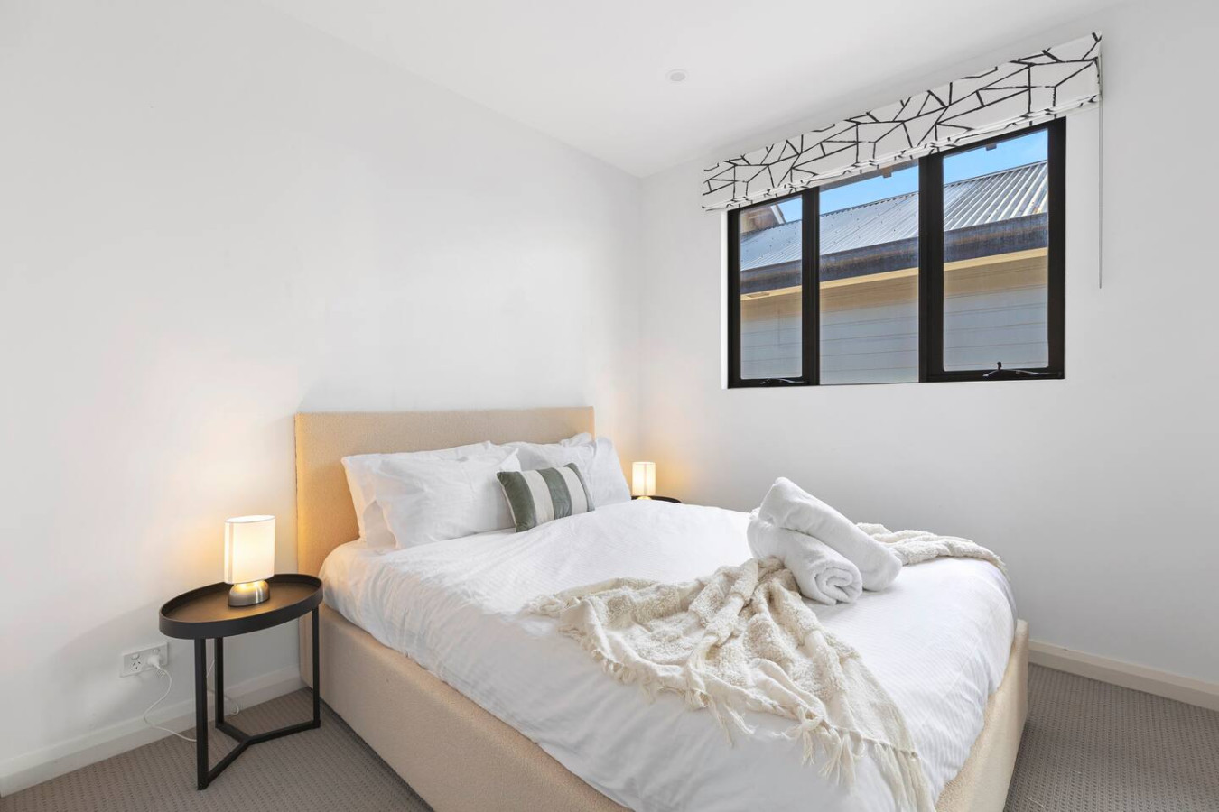 A cozy and modern queen bedroom with soft neutral tones, ambient lighting, and plush bedding, creating a serene and relaxing atmosphere. By Superhostly