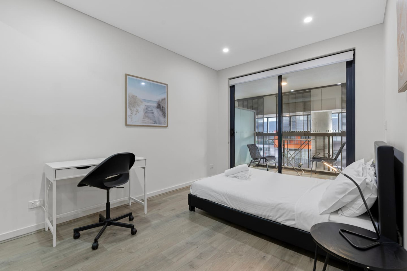 Work and rest comfortably in this serene bedroom setup with a dedicated desk space. By Superhostly