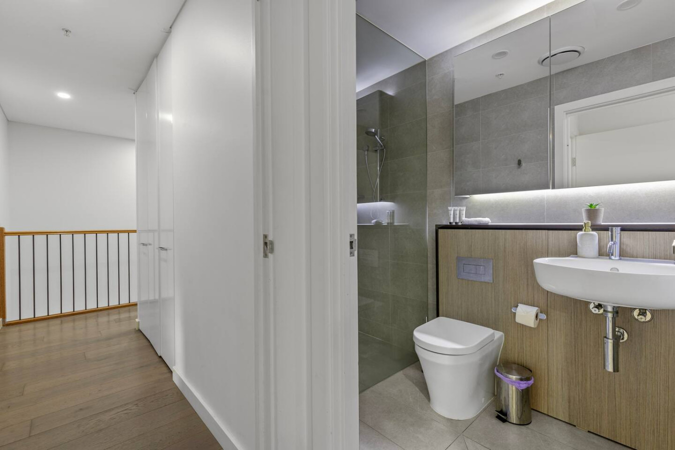 Hallway leading to a sleek bathroom and modern fixtures. By Superhostly