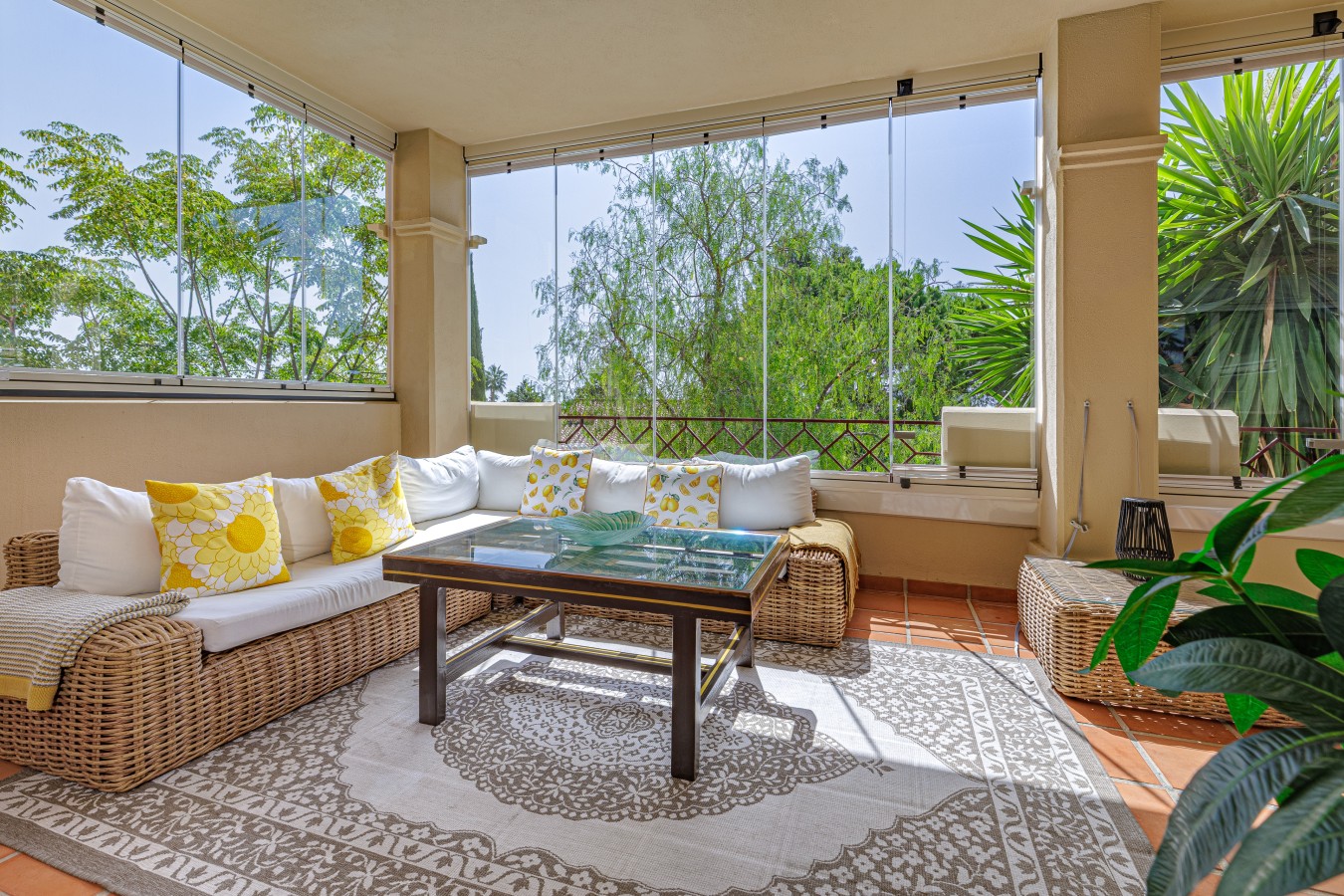 Enclosed Lumon glass terrace with wicker lounge seating, usable year-round