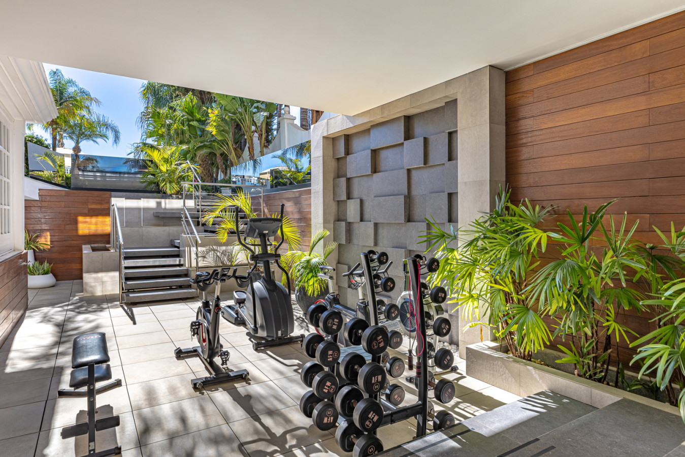 Fully equipped gym featuring free weights, cycling machine, and elliptical machine