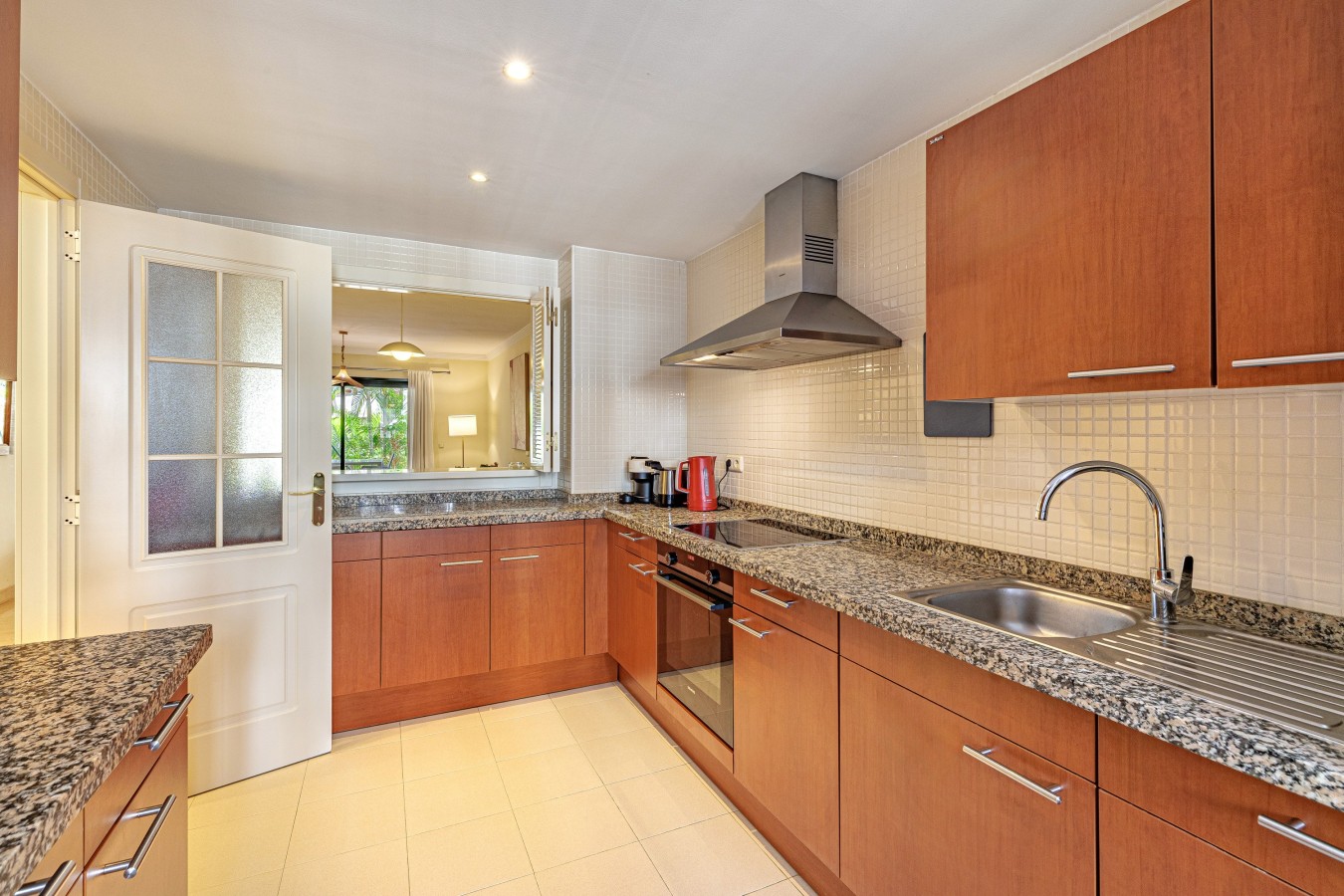 Fully equipped kitchen with oven, granite worktops, and serving hatch to the dining area