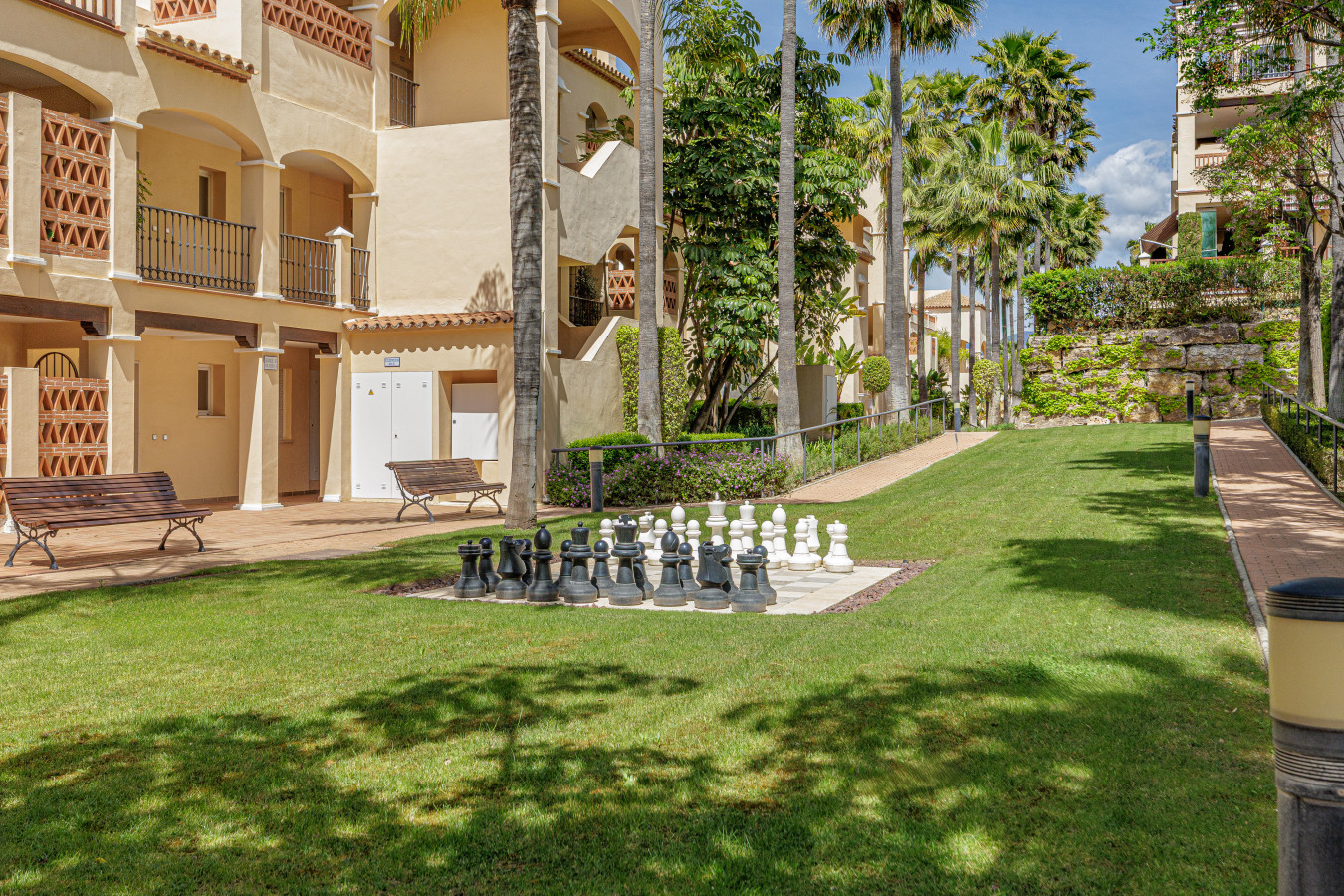 Landscaped Gardens & Amenities: Lush, tropical gardens surround the apartment, featuring a unique giant chess set.