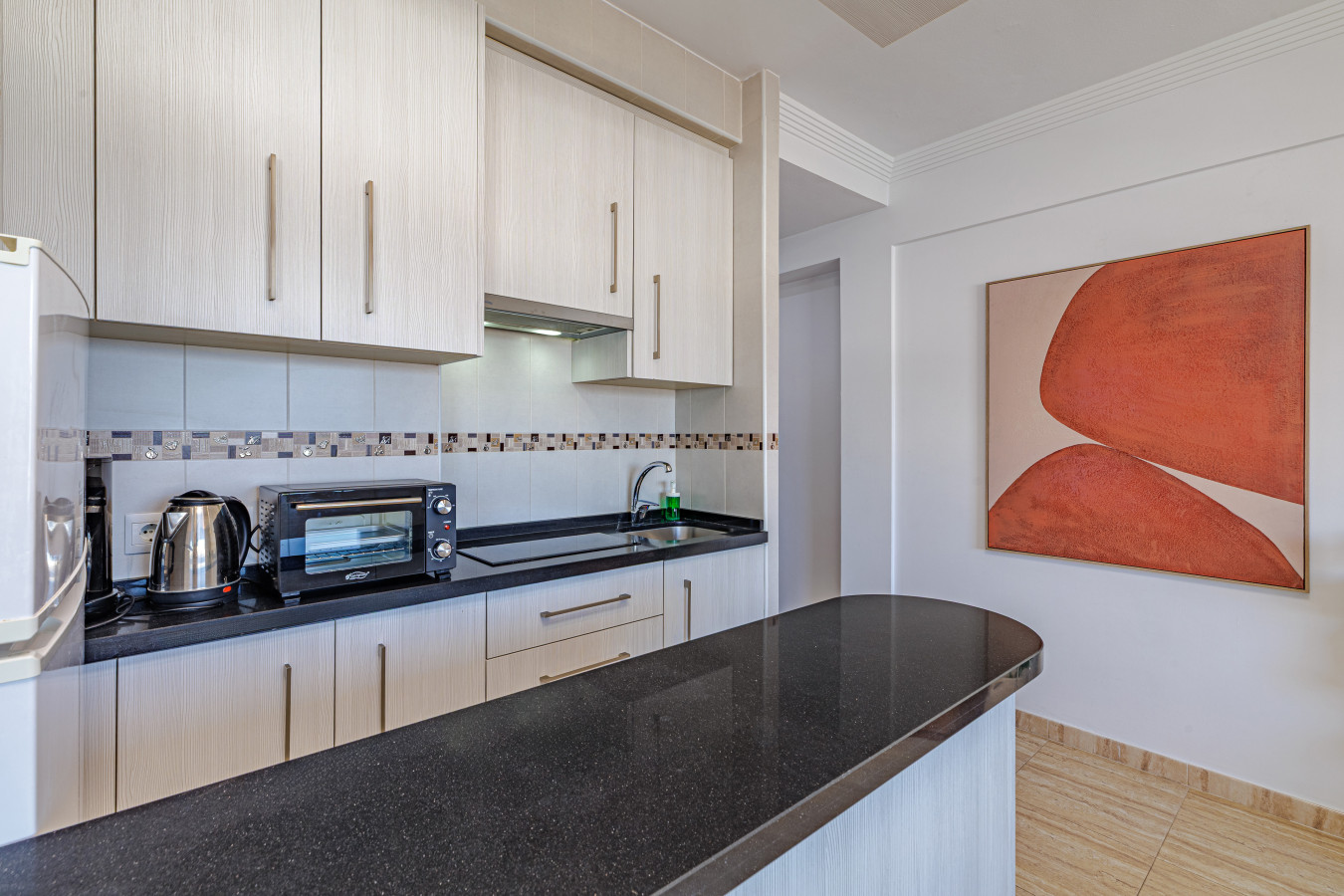 Sleek black countertops, fridge, oven, and all cooking essentials provided.