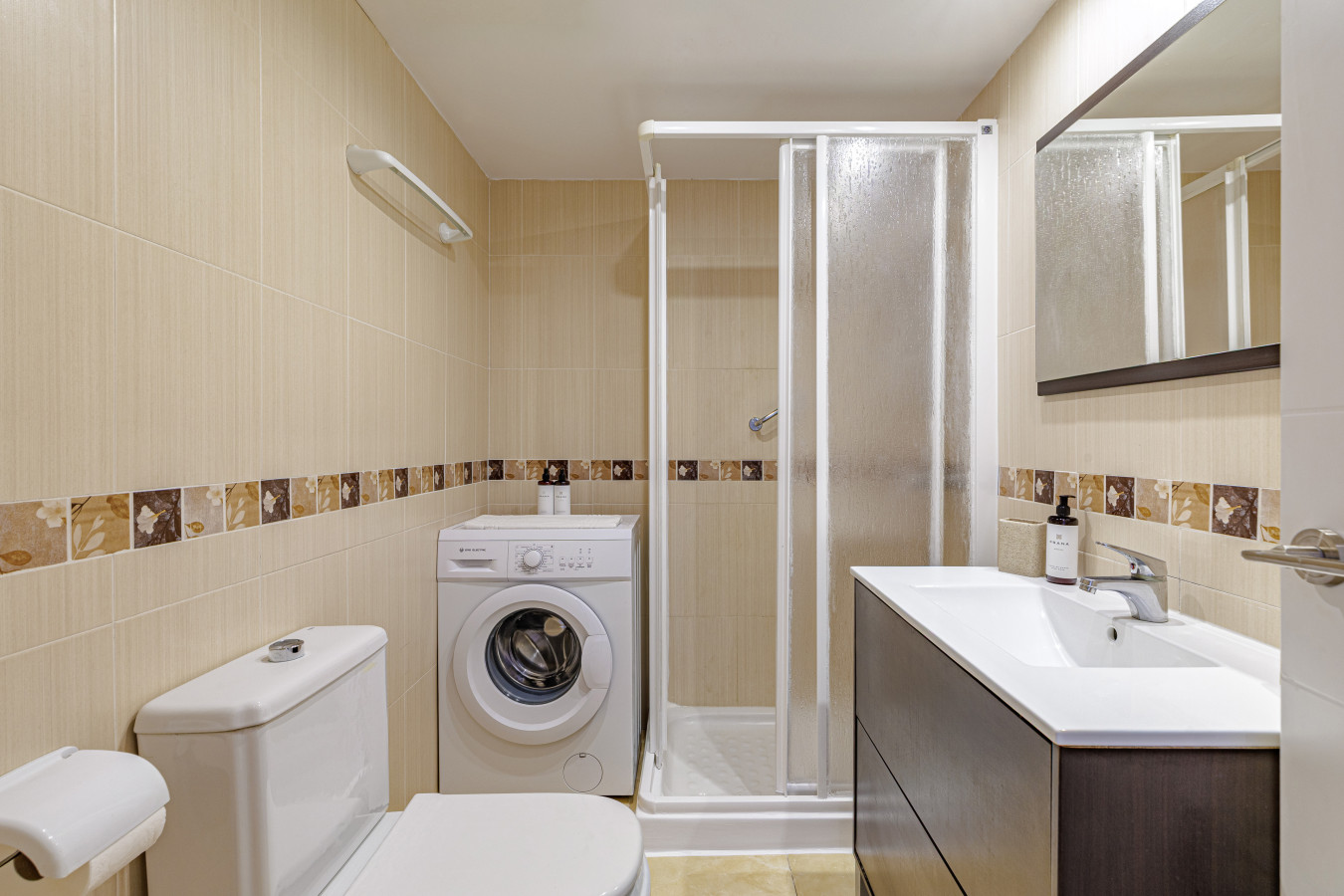 Sparkling clean modern bathroom featuring a walk in shower and washing machine.