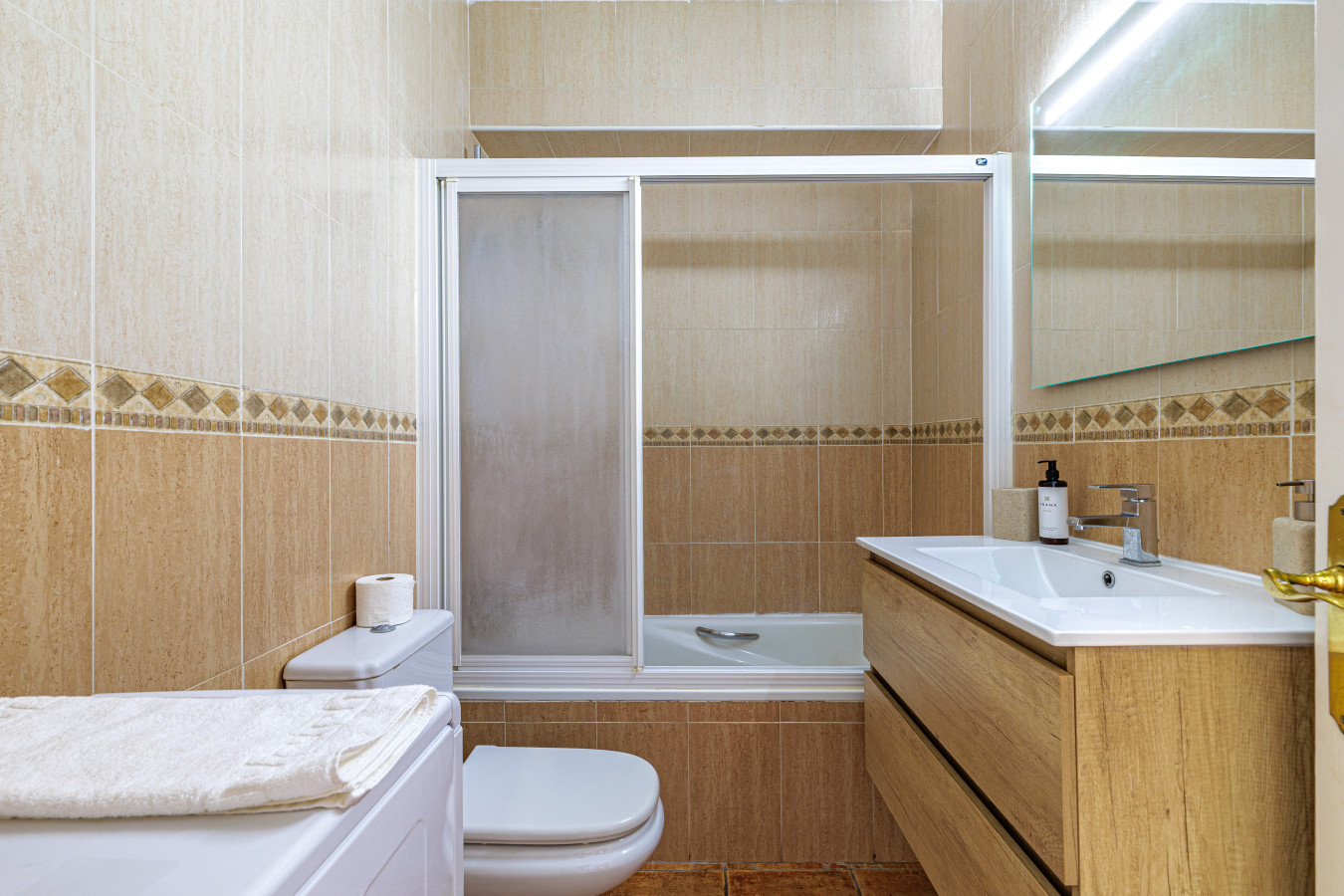 Pristine full bathroom featuring a bathtub, shower, and a convenient in-unit washing machine.