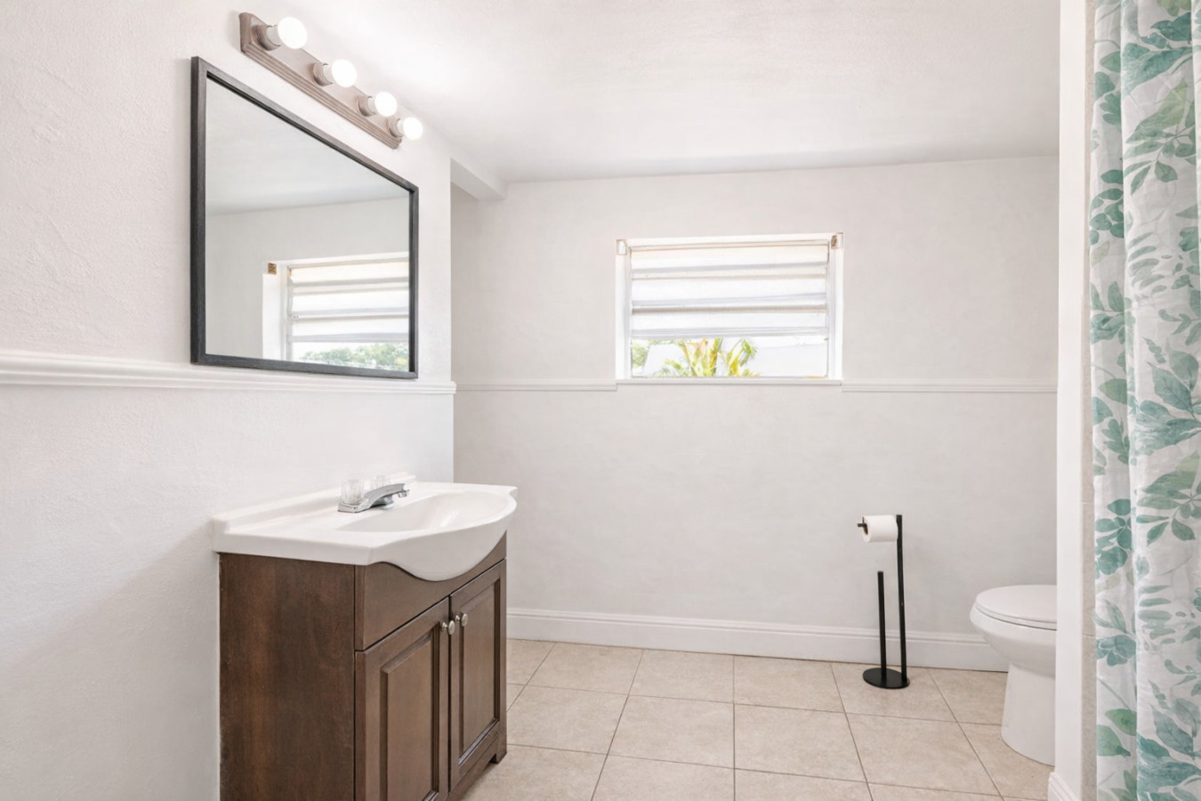 A vanity with mirror stands across from the toilet and shower in this same bathroom.