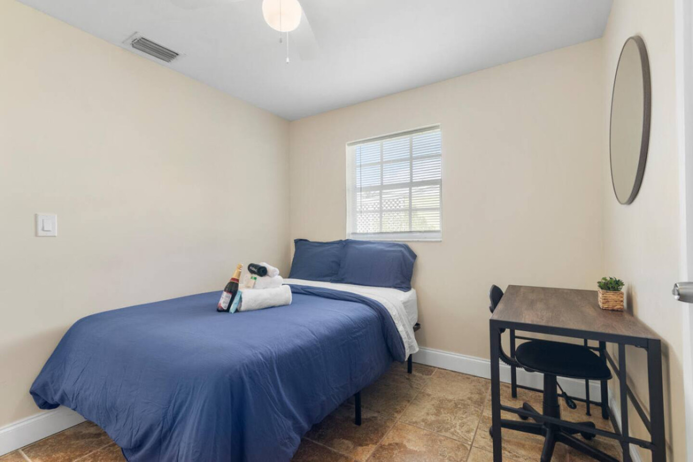 A bedroom bed made up with a welcome set of towels and a bottle of sparkling juice waiting for the guest who checks in.